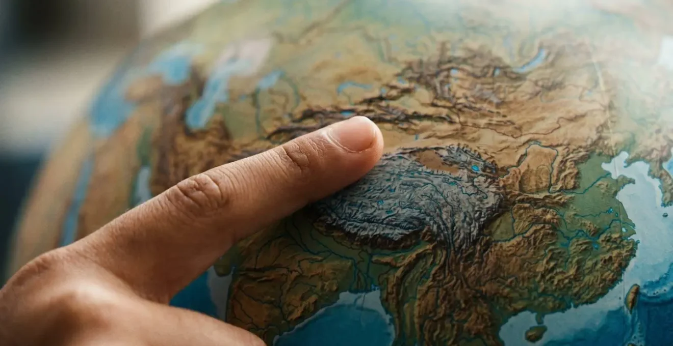 Dedo índice de estudiante trazando una ruta sobre la superficie de un globo terráqueo, aprendizaje kinestésico de geografía