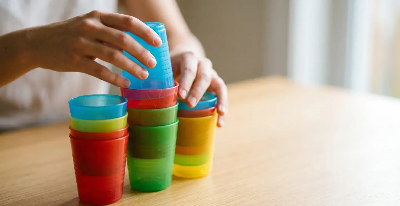 Vasos de plástico de colores apilados en patrones que representan secuencias algorítmicas, actividad educativa desenchufada